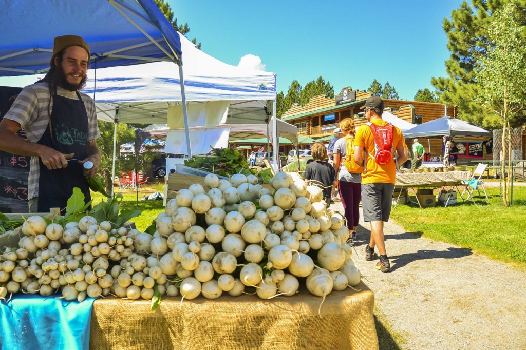 A vendor sells vegetables at the Art and Farmers Market at Frontier Park